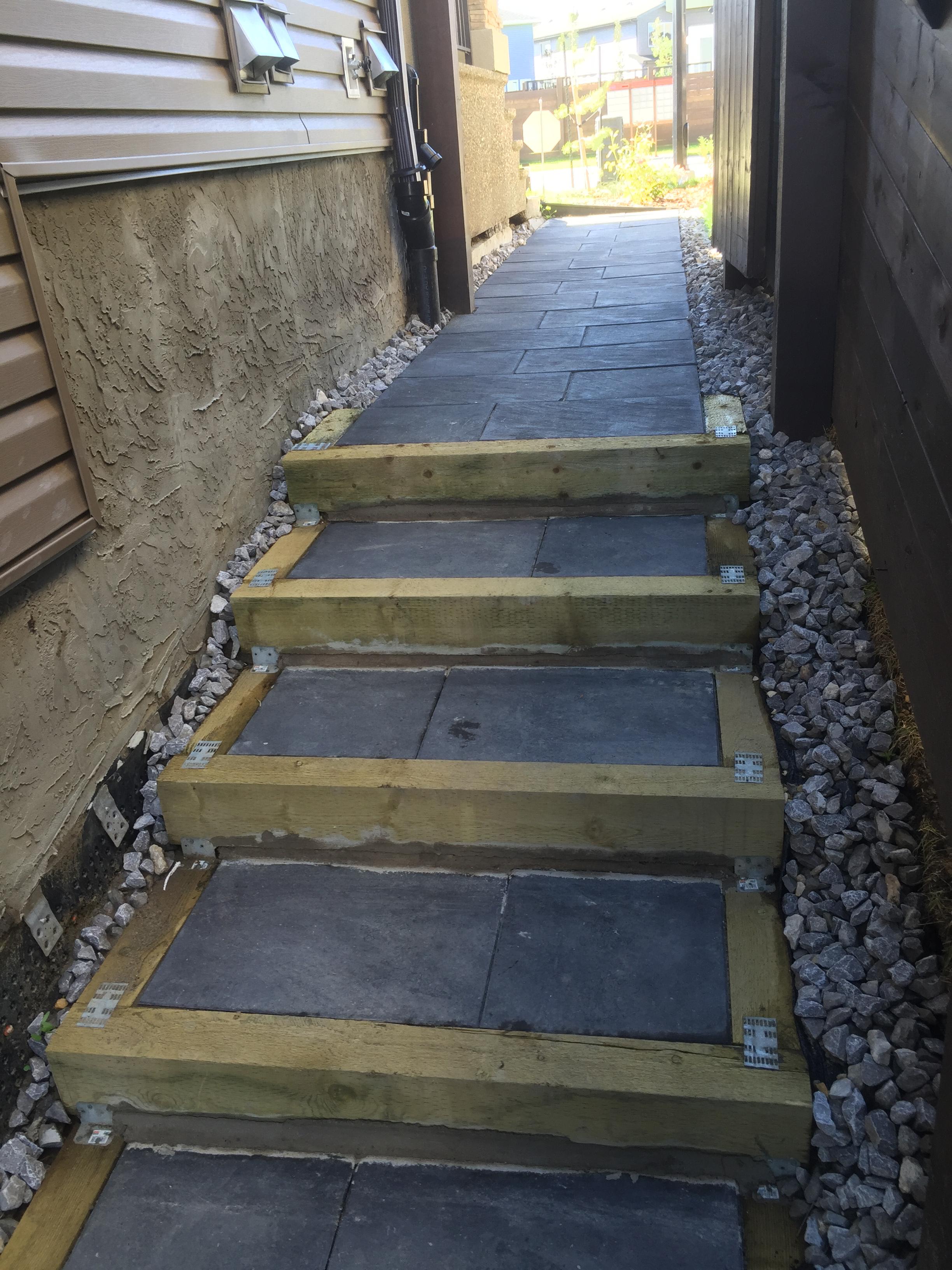 Slate tile staircase with timber risers and gravel surround in side yard